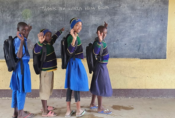 'Thank you woldvision Korea'라고 쓰여진 칠판앞에서 손을 흔들고 있는 학생들