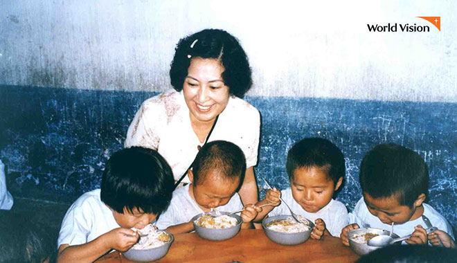 김혜자 친선대사가 국수를 먹고 있는 아이들을 보며 웃고있는 모습. 사진