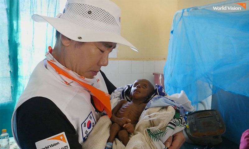 앙상한 뼈만 남은 레이몬드를 안고 있는 박상원 친선대사