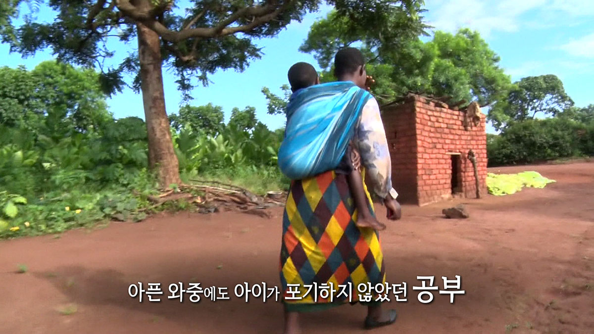 엄마의 등에 업힌 채 학교를 향하던 꿈으로 반짝이는 아이의 눈