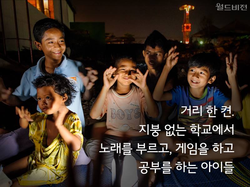 거리 한 켠. 지붕 없는 학교에서 노래를 부르고, 게임을 하고 공부를 하는 아이들