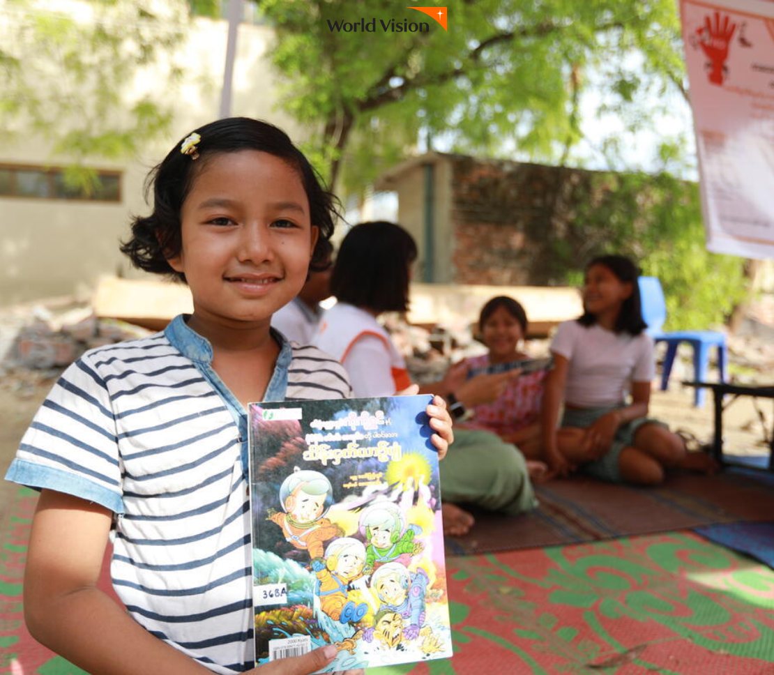 동화책을 들고 활짝 웃고 있는 아동