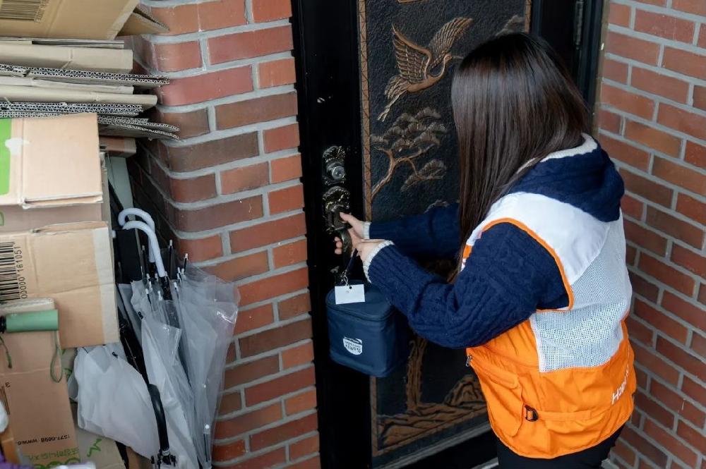 아동의 집 문 앞에 도시락을 배달하는 사회복지사 뒷모습