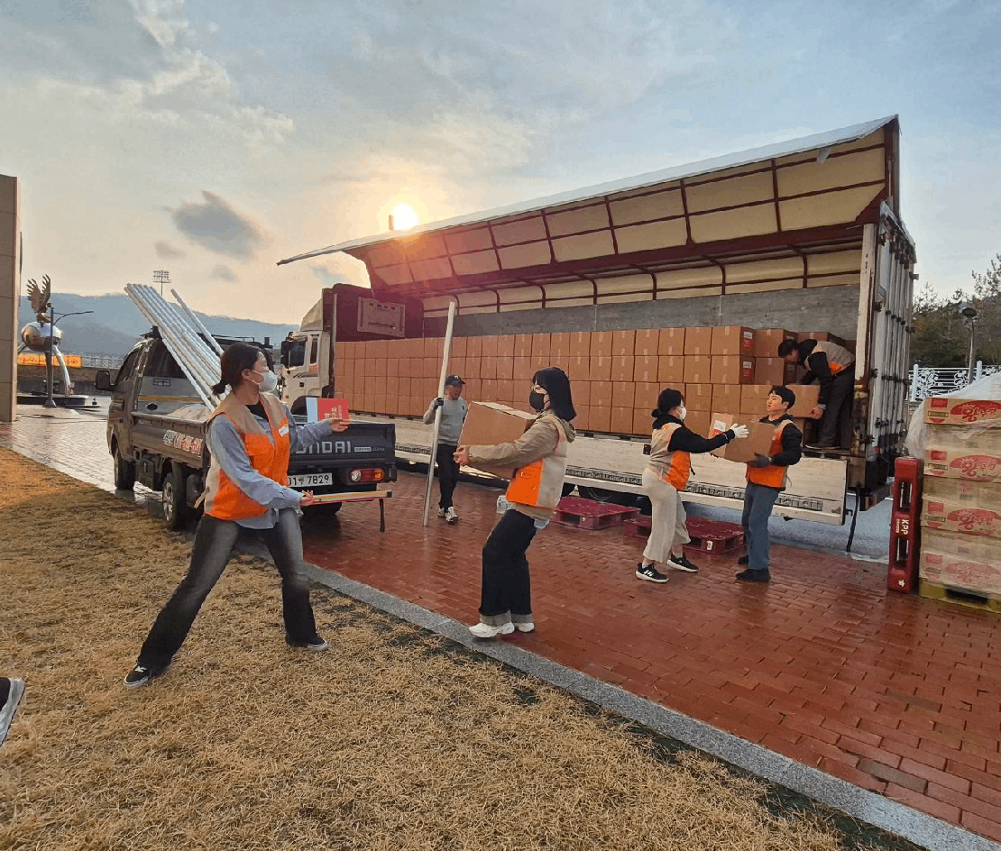 대형 트럭에 있는 구호물품들을 나르고 있는 월드비전 직원 5명