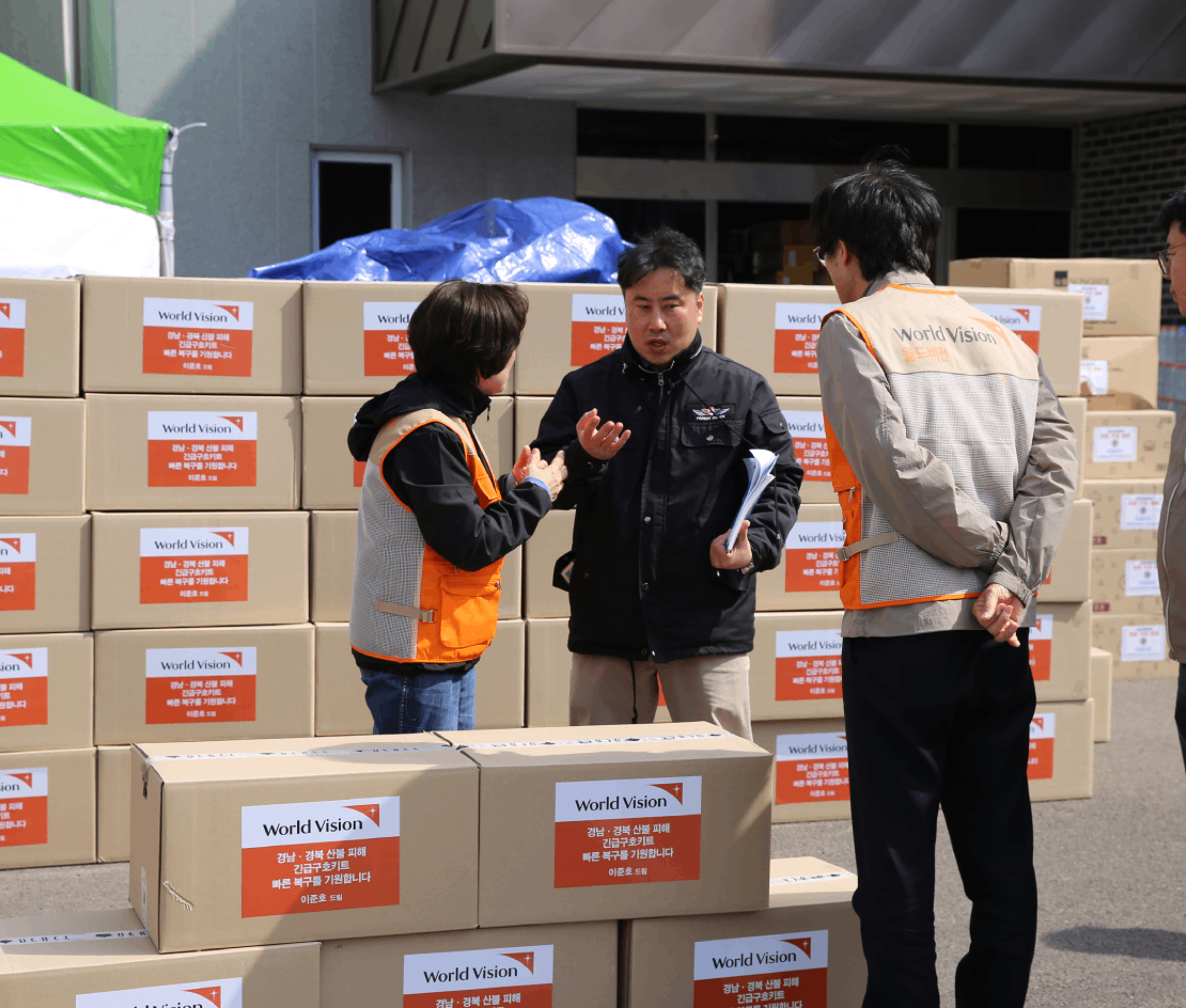 구호품을 전달하고 있는 월드비전 직원 2명과 관계자 1명