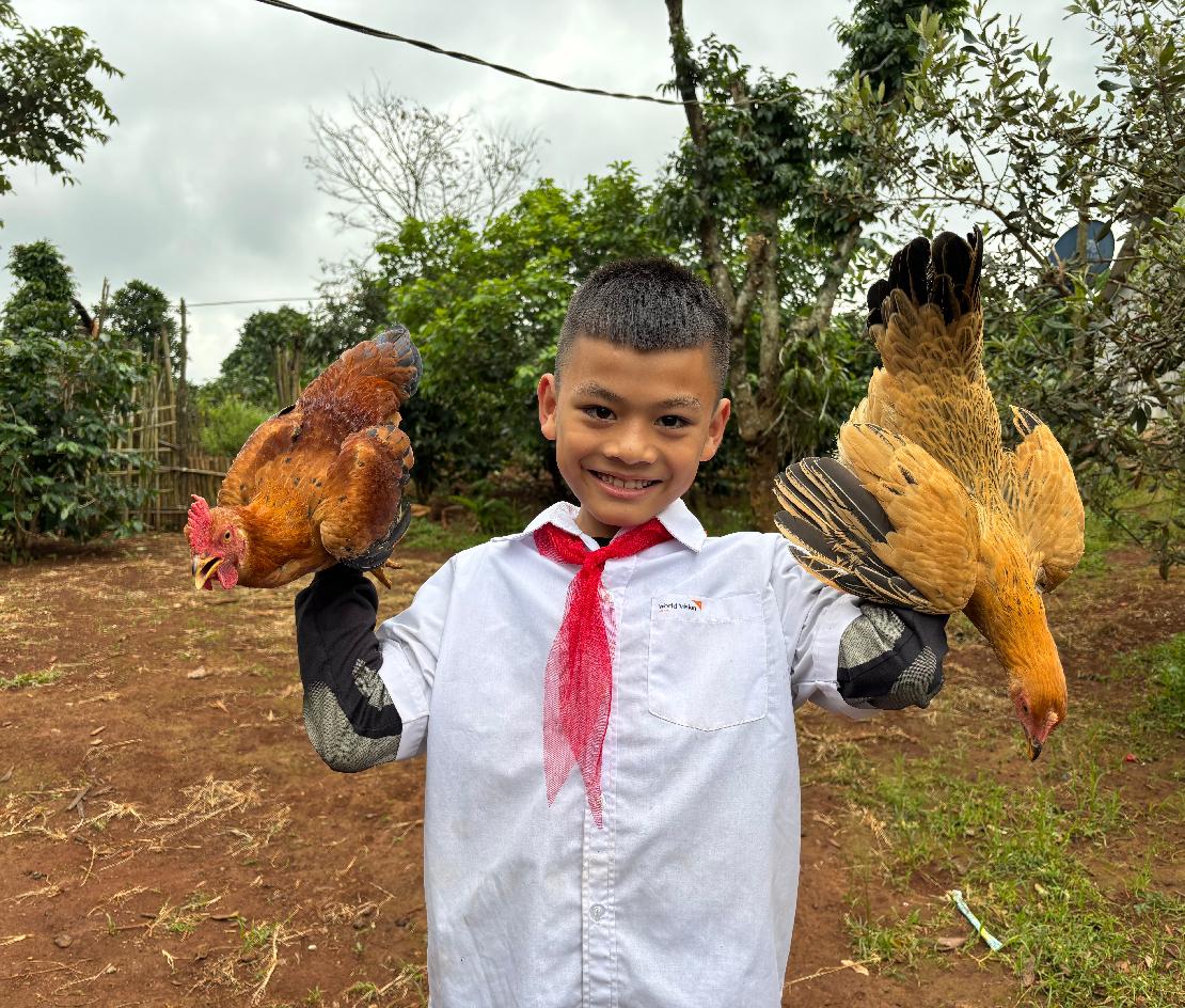 닭을 들고 미소짓느 베트남 아동