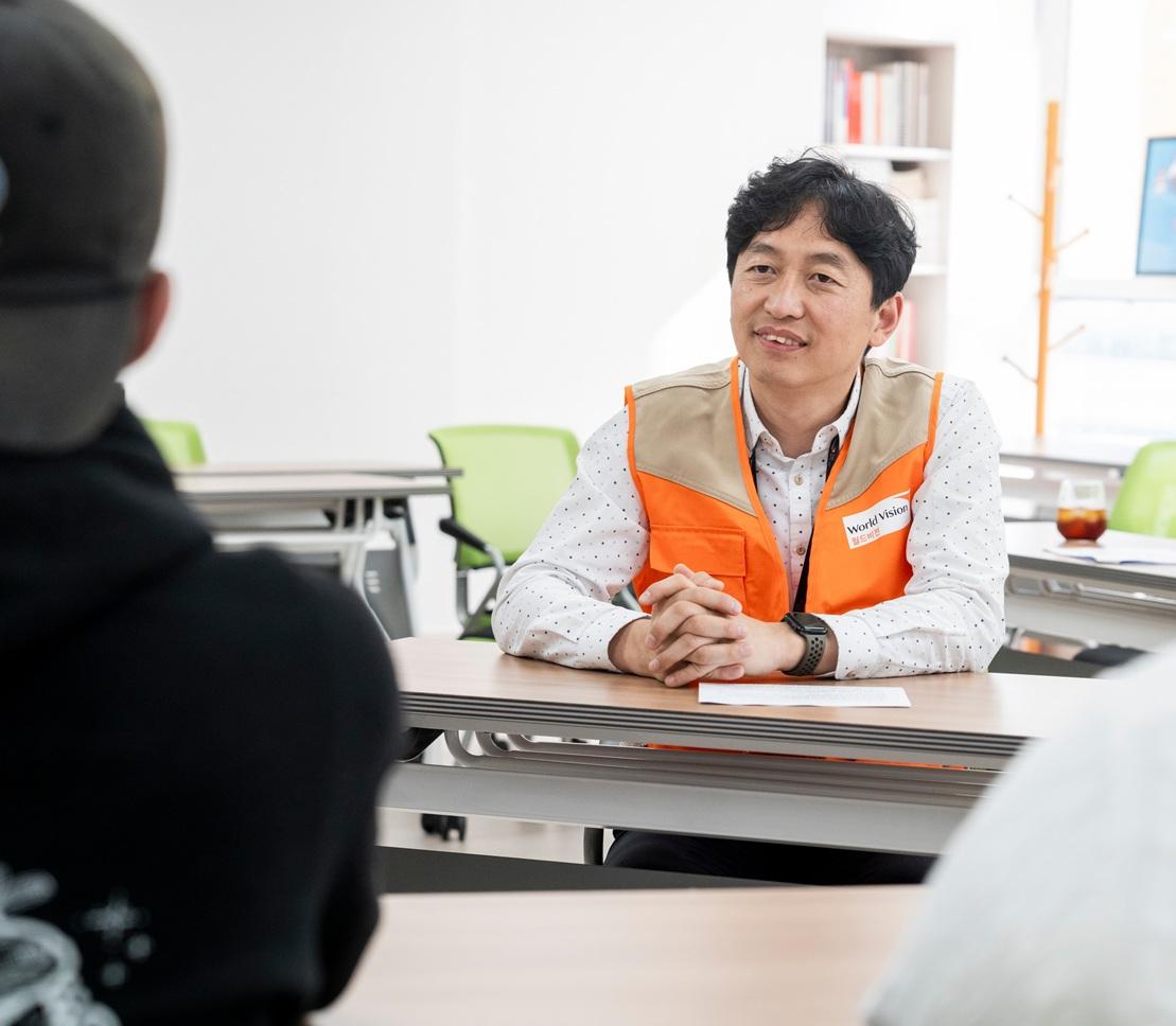 책상에 앉아 청년 이야기를 듣는 월드비전 부산사업본부 참여나눔팀 최원용 팀장